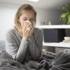 Femeie răcită care își suflă nasul