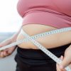 femeie cu obezitate isi masoara circumferinta abdominala